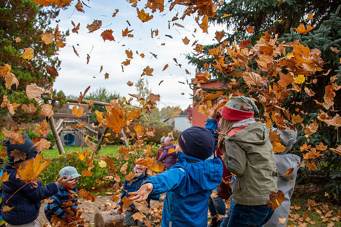Kinder spielen im Herbst mit Blättern